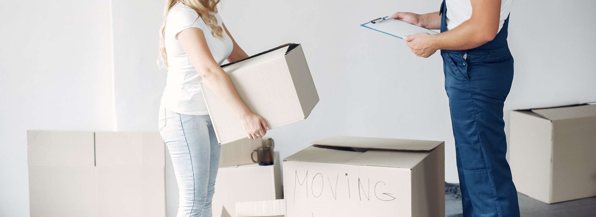 femme-porte-un-carton-devant-demenageur- Femme porte un carton de déménagement avec un déménageur